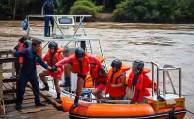 Viajeros embarcando en el gomón con asistencia del guía en el Puerto Macuco, inicio de la navegación.